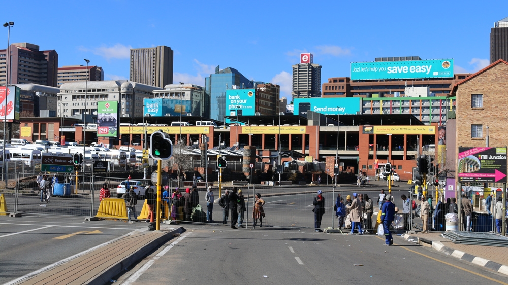 Homeless people line up outside the security fence hoping to be let in to collect sleeping bags and donated clothes from the CEO SleepOut on Nelson Mandela Bridge [Caelainn Hogan/Al Jazeera]