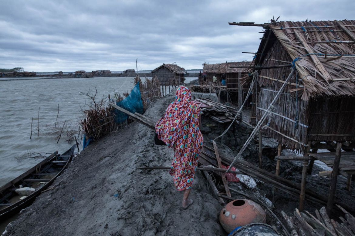 A women return home just after the storm in a coastal area of Bangladesh. 17 people were killed in ten districts of the country, as a number of houses collapsed and trees were felled by gusts in the l