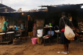 A woman stands outside a shop at the end of a night-long curfew ordered by Kenya''s President Uhuru Kenyatta to slow the spread of the coronavirus disease (COVID-19), in Nairobi