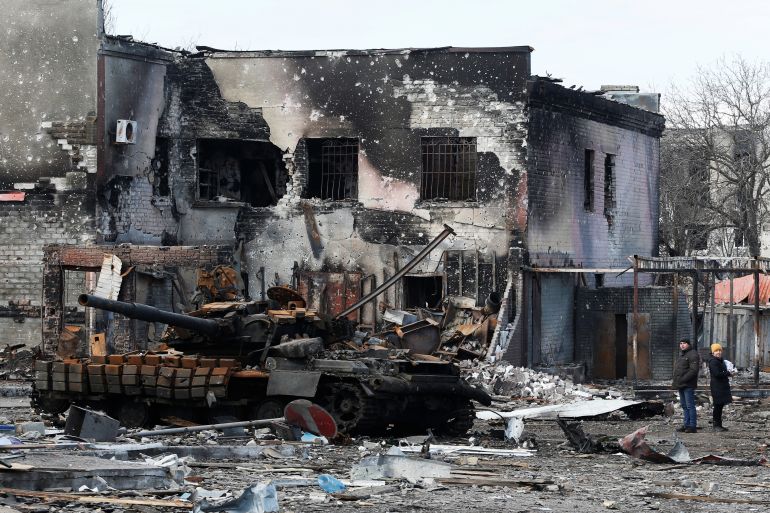 Local residents are seen next to a destroyed armoured vehicle during Ukraine-Russia conflict in the separatist-controlled town of Volnovakha in the Donetsk region, Ukraine March 15, 2022.