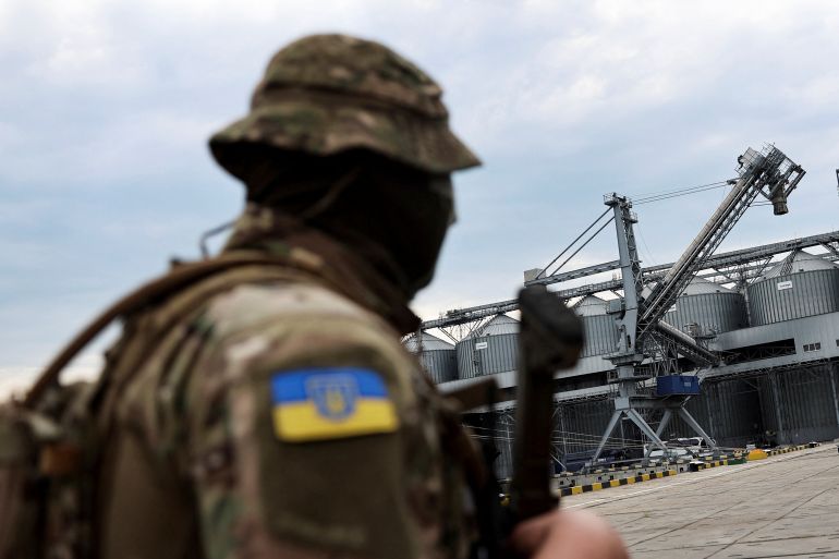 A Ukrainian serviceman stands in front of silos of grain at the Chernomorsk port in the Odesa region.