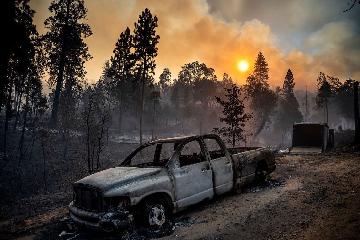 The Oak Fire burns behind a scorched pickup truck in the Jerseydale community