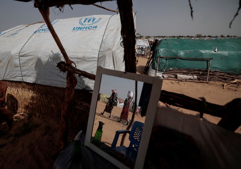 Sudanese women who fled the conflict in Sudan's Darfur region carry their food supply as they walk toward their makeshift shelters in Adre, Chad
