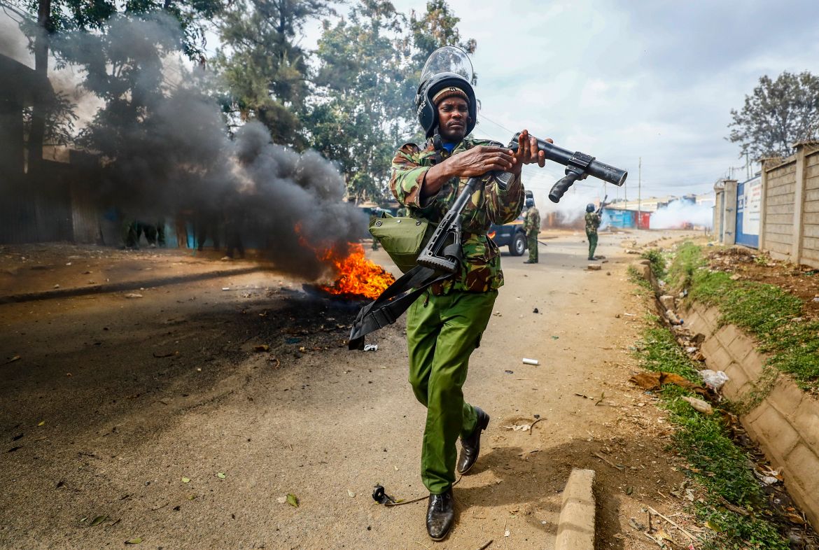 A riot policeman reloads a teargas grenade launcher