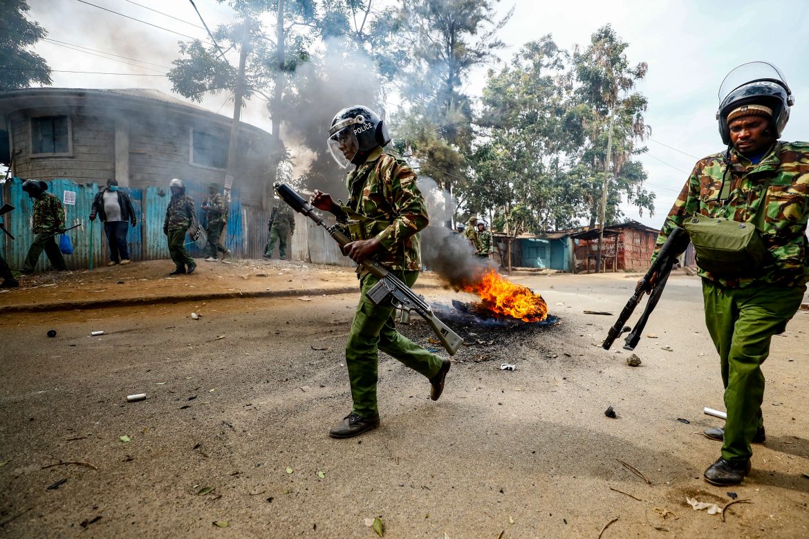 Riot policemen walk past a burning barricade