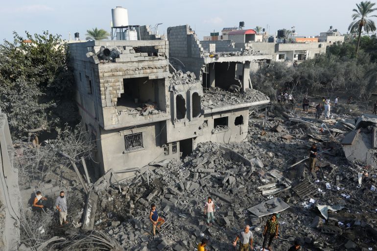Palestinians gather on rubble near damaged buildings in the aftermath of Israeli strikes, in Khan Younis in the southern Gaza Strip