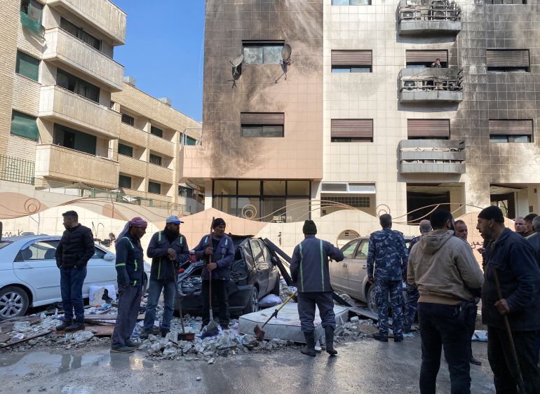 Workers and people stand near a damaged building after, according to Syrian state media reports, several Israeli missiles hit a residential building in the Kafr Sousa district, Damascus, Syria February 21, 2024. REUTERS/Firas Makdesi