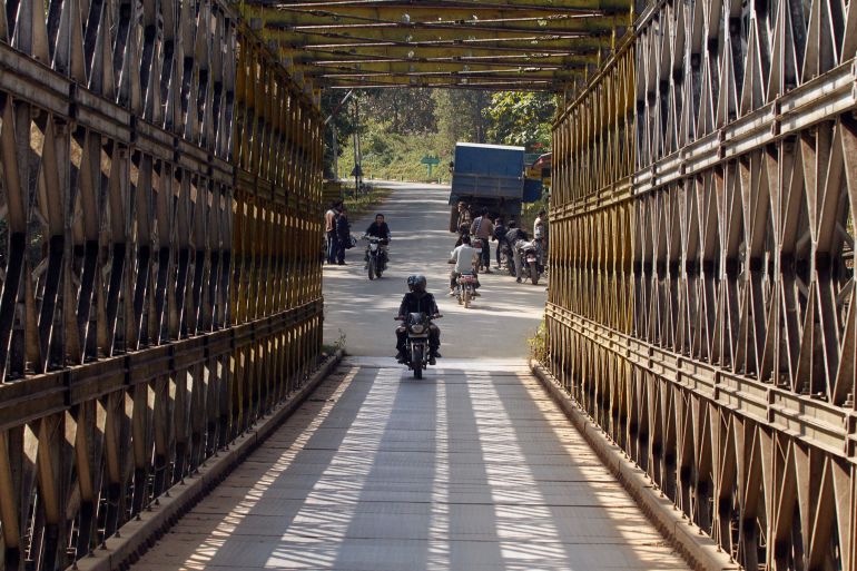 People ride motorbikes as they cross a border bridge.
