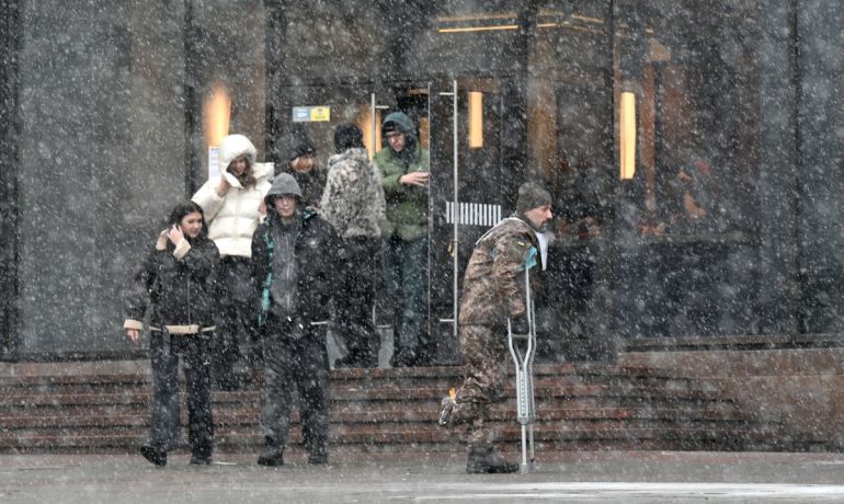 A wounded Ukrainian serviceman walks in a street in Kyiv during snow fall on February 15, 2026, amid Russian invasion in Ukraine. (Photo by Sergei SUPINSKY / AFP)