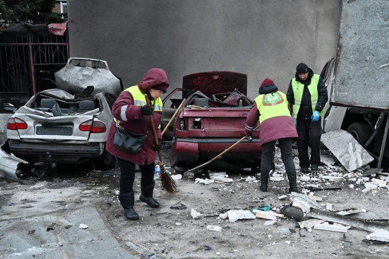 Communal workers clear debris next to destroyed cars in the courtyard of a damaged residential building following an air attack in Kharkiv on February 26, 2026, amid the Russian invasion of Ukraine.