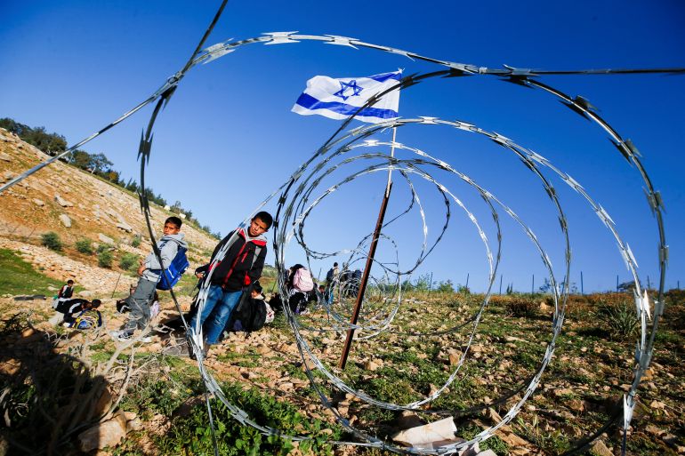 Palestinian students gather near a fence erected by Israeli settlers